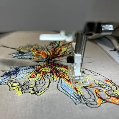 Closeup of the Butterfly 'Let It Be' embroidery design showcasing intricate stitching for various fabric items.