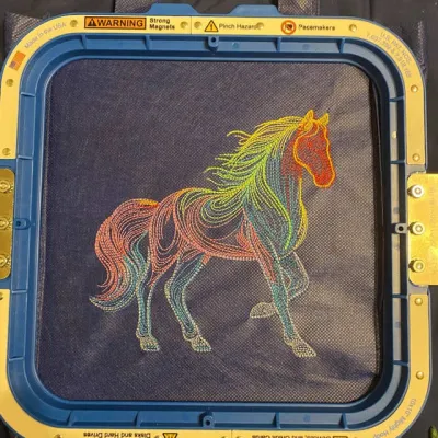 Closeup of rainbow horse sketch embroidery design showcasing intricate stitching patterns on fabric.