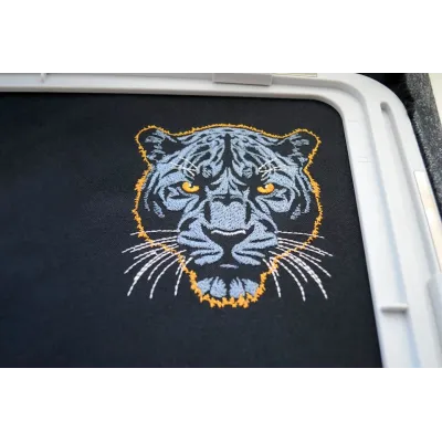 Closeup of dark blue panther embroidery design on a dark background, showcasing intricate stitching details.